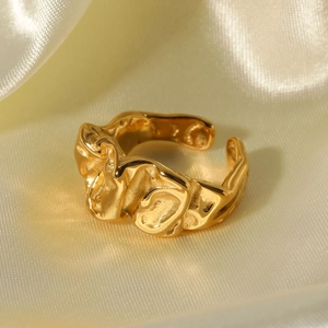 Golden irregular lava texture open ring made of titanium steel on beige silk background