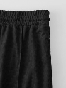 Detailed macro view of black waffle knit textured fabric and elastic waistband on joggers