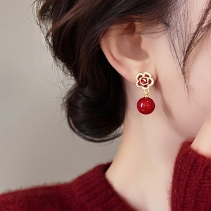 Boucles d'oreilles fleurs zircon plaqué or et perles rouges sur un mannequin féminin