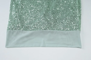 Detailed macro view of light green sequin fabric and smooth hem of the slim evening dress