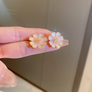 Close-up of sweet pink cherry blossom stud earrings with gold edges and small beads