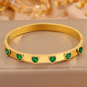 Gros plan détaillé du bracelet en acier doré orné de six zircons verts en cœur