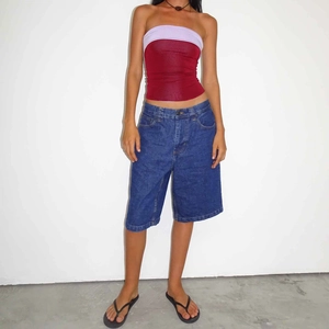 Slim fit denim shorts paired with a contrast red and purple mesh tube top on a model