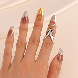 Macro detail of adjustable cubic zirconia nail rings in gold and silver on silk fabric