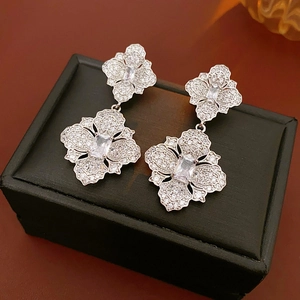 Détail de boucles d'oreilles fleurs argentées avec un grand zircon carré et cristaux