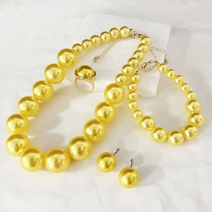 Detailed set of yellow pearl necklace, bracelet, earrings and ring on white display