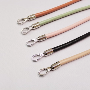 Detailed view of leather bag straps in multiple colors with silver metal spring hooks