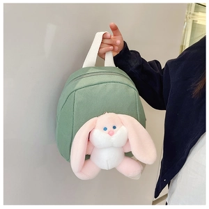 Detail of green canvas toddler backpack featuring a cute 3D pink bunny plush pendant