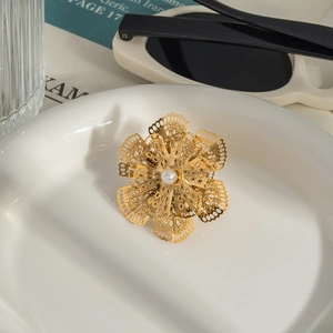 Close-up of a hollow camellia brooch with white pearl on a porcelain plate
