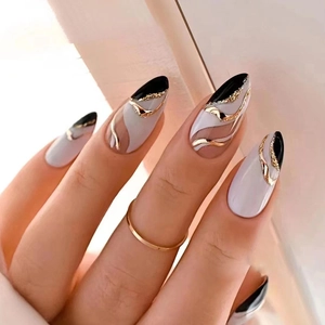 Elegant almond press-on nails with black, white, and gold wave patterns and glitter