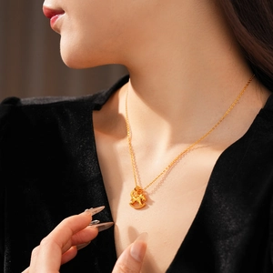 Close-up of a gold-plated necklace featuring a dangling rocking horse pendant on a model