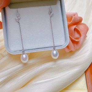 Close-up of long pearl drop earrings with silver tassels and leaf design in a gift box