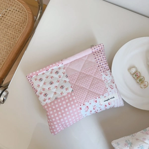 Close-up of pink floral quilted patchwork makeup bag with simple wish label on desk