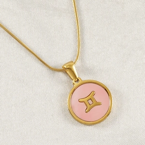 Detail of 18K gold titanium necklace with pink Gemini constellation pendant on white fabric