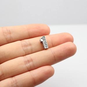Macro detail of silver number 1 charm with four small rhinestones for DIY jewelry making