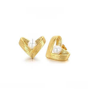 Detailed view of gold-tone hollow heart earrings with shell pearl and brushed texture