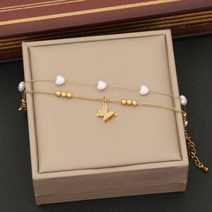 Détail d'un bracelet doré double couche avec papillon givré et cœurs blancs élégants
