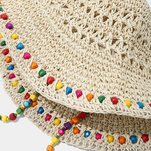 Détail d'un chapeau de paille avec perles en bois colorées et texture de crochet artisanale