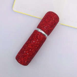 Refillable 10ml red rhinestone perfume atomizer bottle shown on an open notebook