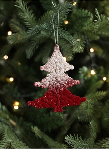 Close-up of a red and white gradient flocked Christmas tree ornament hanging on a festive branch
