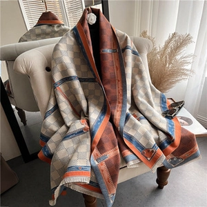 Detail view of plaid cashmere scarf with belt pattern draped on soft armchair