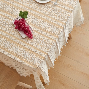 Detail of beige lace tablecloth with hollow geometric patterns and elegant tassels