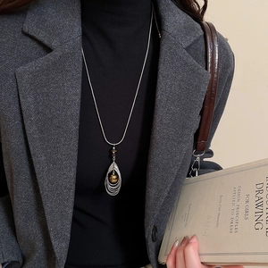 Long sweater necklace with zircon beads and a hollow teardrop pendant on a model