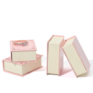 Pink book-shaped jewelry box set with rose gold solitaire ring display on top