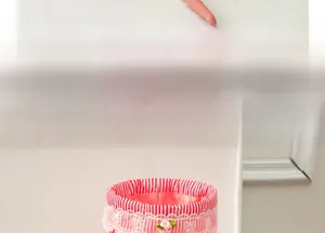 Detail of red striped fabric storage basket with lace trim and pink floral accent