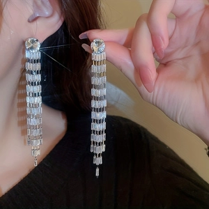 Close-up of elegant long tassel earrings with sparkling crystals on a silver setting