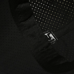 Close-up of black breathable mesh baseball cap fabric featuring a white embroidered logo
