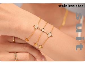 Detail showing the polished gold clover charm with shimmering zircon pavé on the bracelet