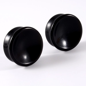 Macro detail of solid black stone double flared ear gauges with smooth polished finish