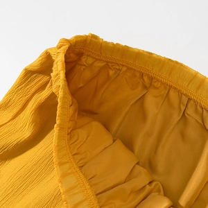 Detailed macro view of yellow pleated fabric texture and elastic waistband stitching