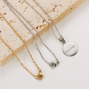 Detail of silver and gold necklaces with Merry & Bright engraved circular pendants