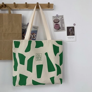 Detail view of cream canvas tote bag with green abstract art and rabbit illustration