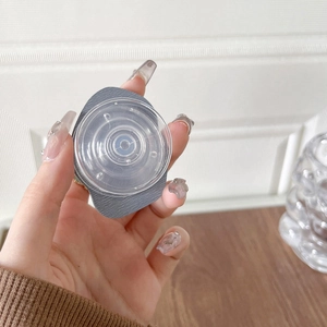 Close-up of a circular collapsible phone grip with gray base and clear texture finish
