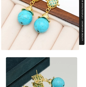 Detailed macro view of turquoise teardrop earrings with golden textured metal accents