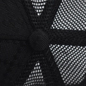 Close-up of the black trucker hat featuring mesh panels and a fabric-covered top button