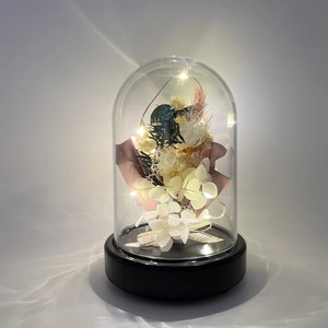 Macro shot of preserved flowers with LED string lights inside a clear glass dome display
