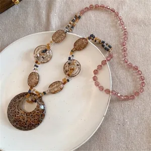 Gros plan d'un pendentif rond imprimé léopard sur un collier bohème en perles