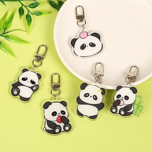 Cute acrylic panda keychains featuring five cartoon poses on a fresh green background