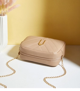 Detail of beige quilted crossbody bag with V-shaped texture and elegant gold chain strap