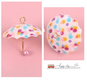 Detailed view of colorful polka dot umbrella jewelry charms with pearl details