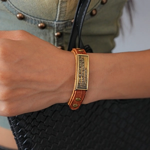 Detailed macro view of vintage brown leather bracelet with engraved bronze metal plate