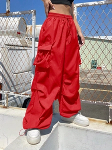 Close-up of red cargo pants with large side pockets and drawstring hem on a model