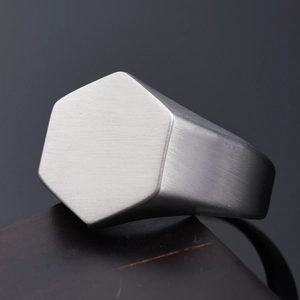 Macro view of a matte brushed silver hexagonal signet ring with geometric industrial design