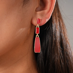 Close-up of elegant red geometric long earrings with gold trim on model ear