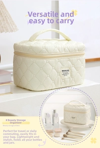 Detailed view of cream quilted cosmetic bag with handle and dual zipper closure