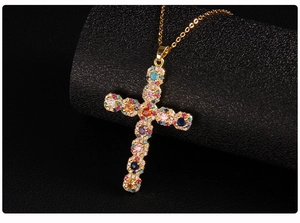 Detailed macro view of gold cross pendant with colorful zircon stones on black display